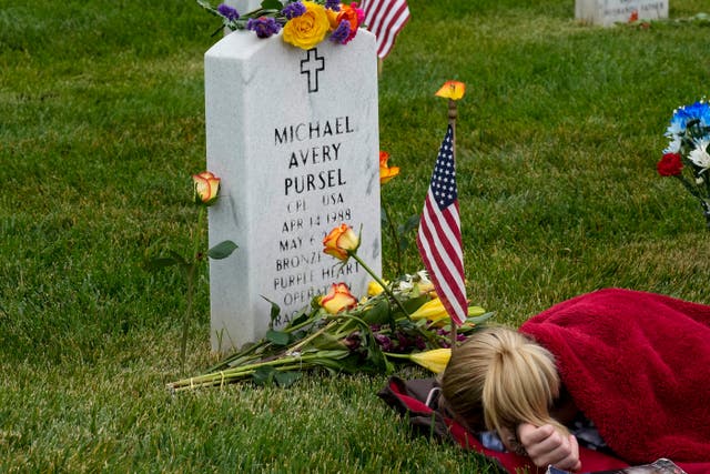 Avery Carlin rests by the headstone of her uncle US army corporal Michael Avery Pursel as she visits Section 60 at Arlington National Cemetery with her family on Memorial Day