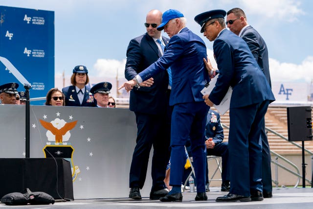 President Joe Biden points to sandbags after falling on stage during the 2023 United States Air Force Academy Graduation Ceremony at Falcon Stadium, at the United States Air Force Academy in Colorado Springs, Colorado