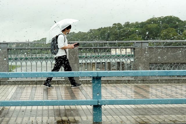 A person walks in the rain Friday in Tokyo, as a tropical storm was approaching