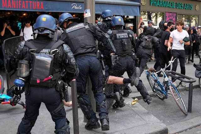 Riot police officers detain a person during a protest in Paris, France