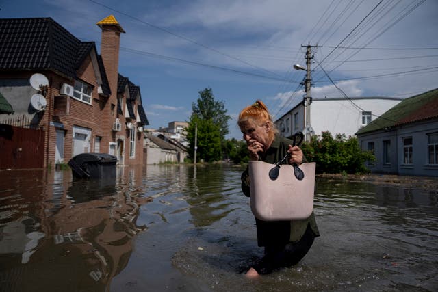 A local resident makes her way through a flooded road after the walls of the Kakhovka dam collapsed overnight, in Kherson, Ukraine 