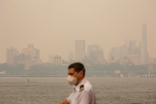 A crew member wearing a face mask is seen in a haze-filled sky on Staten Island Ferry in New York