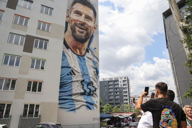 People take pictures with their phones of a mural portraying Argentinian footballer Lionel Messi in Tirana, Albani