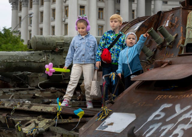 Children stand on top of a burned out Russian tank in St Michael’s Square in Kyiv