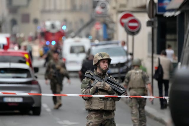 A soldier secures the area as firefighters tackle a blaze in Paris