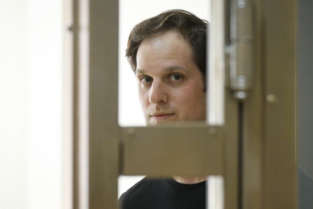 Evan Gershkovich stands in a glass cage in a Moscow courtroom in June