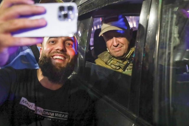 Yevgeny Prigozhin, the owner of the Wagner Group military company, right, sits inside a military vehicle posing for a selfie with a local civilian on a street in Rostov-on-Don, Russia, on Saturday