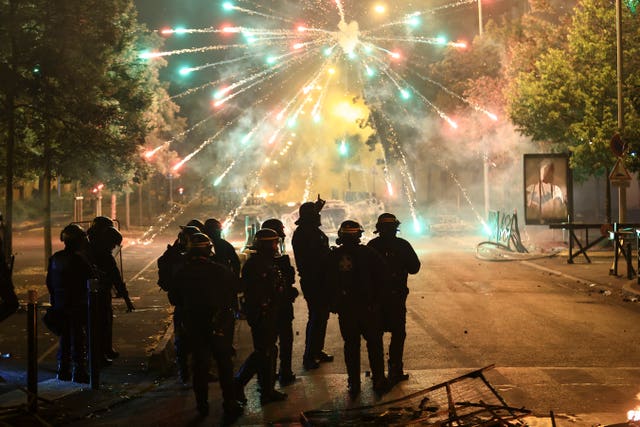 Police stand amid firecrackers on the third night of protests sparked by the fatal police shooting of a 17-year-old driver in the Paris suburb of Nanterre, France