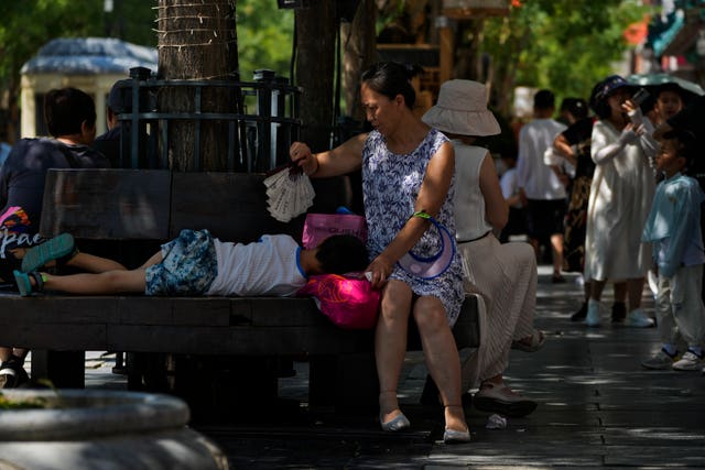 A woman uses a fan to cool a child in Beijing