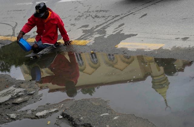 A homeless physically disabled man navigates his way across a puddle to ask for alms outside a mosque in Kathmandu, Nepal