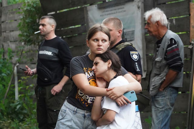 Young women hug each other near their apartment building, which was damaged by a Russian attack in Sumy, Ukraine, on Monday