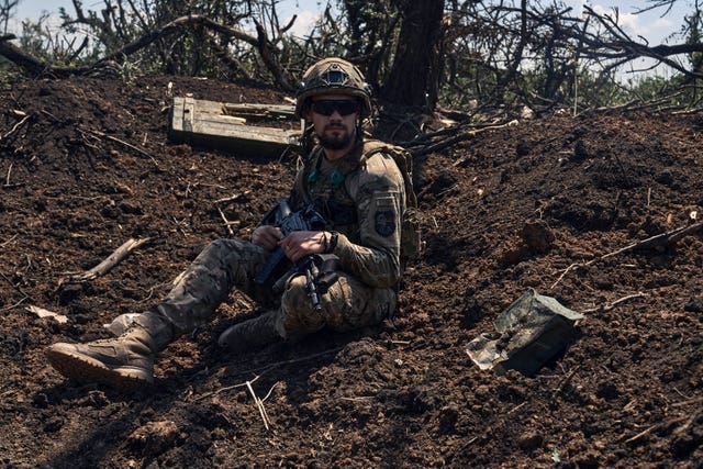 A Ukrainian soldier sits in a recently captured Russian trench on the frontline near Bakhmut, Donetsk region