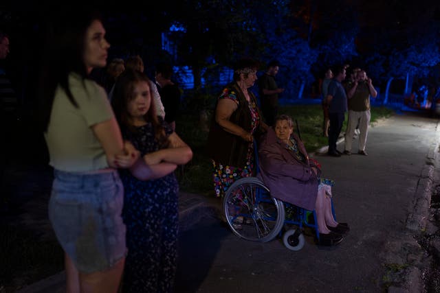 Residents stand outside an apartment building damaged in Russia’s air attacks in Kyiv, Ukraine