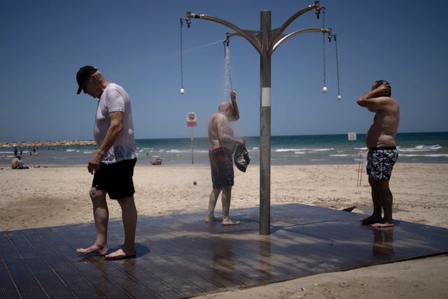 Men shower at a public beach as they take refuge from a summer heatwave in Tel Aviv on Thursday