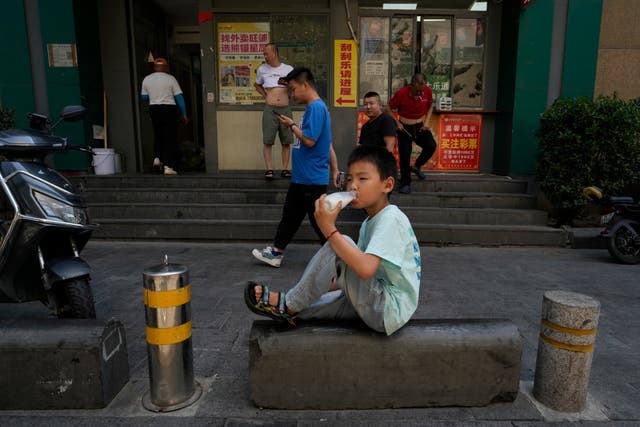 A boy drinks water on the street