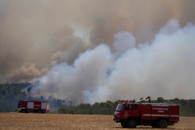 Fire engines parked in a field near wildfires in Inoi, near Athens, Greece