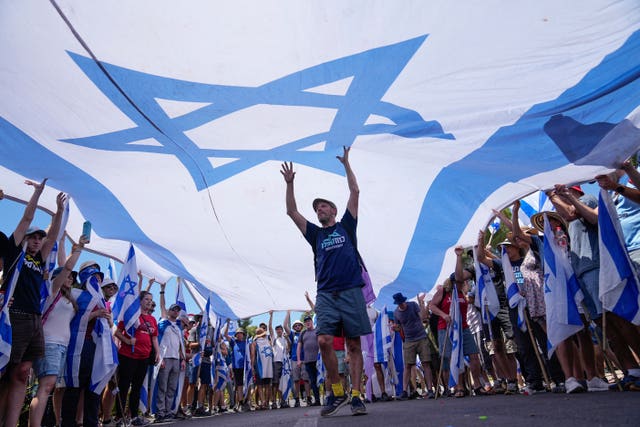 Demonstrators wave a large Israeli flag during a protest against plans by Prime Minister Benjamin Netanyahu’s government to overhaul the judicial system, outside the Knesset, Israel’s parliament, in Jerusalem