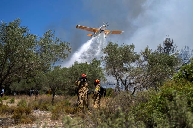 An aircraft drops water during a wildfire in the village of Vati, on the Aegean Sea island of Rhodes in Greece