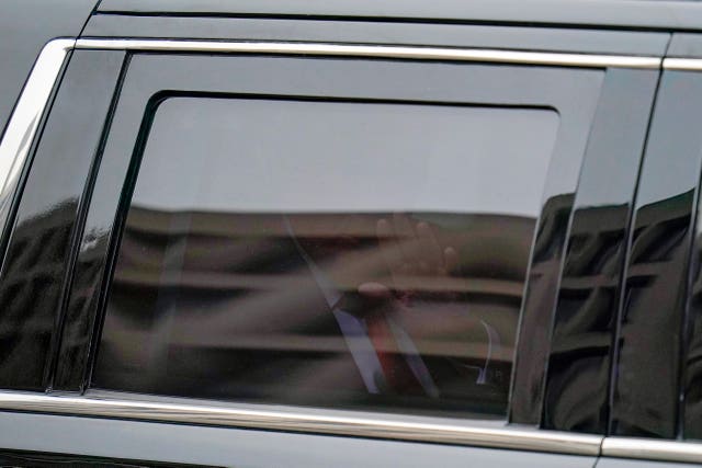 Mr Trump waves from his motorcade as he leaves the E Barrett Prettyman US Federal Courthouse