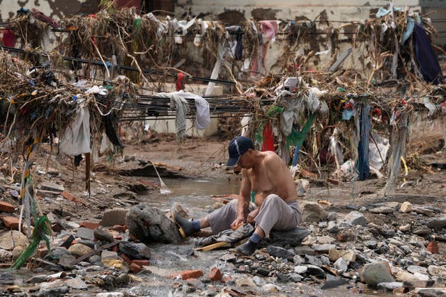  A man washes his clothes in a stream near debris 