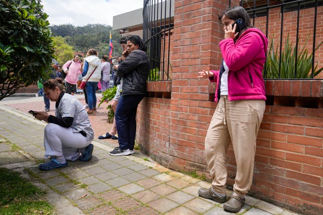Residents wait outside their homes