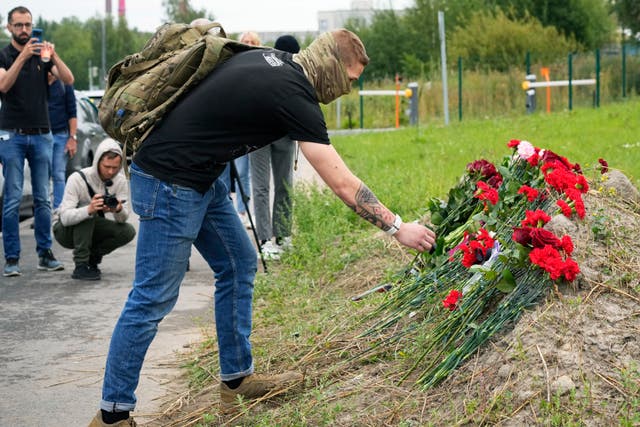 A man lays flowers at an informal memorial next to the former PMC Wagner Centre in St Petersburg, Russia 