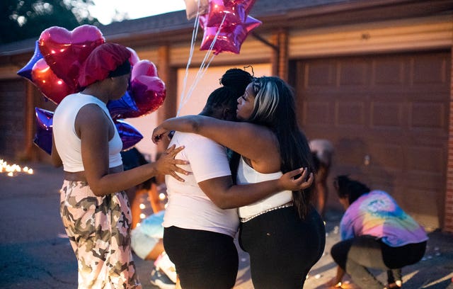 Friends comfort each other at a private candlelight vigil on Friday