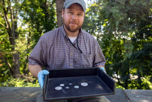 West Point archaeologist Paul Hudson displaying coins found in the lead box believed to have been placed in the base of a monument by cadets almost two centuries ago, in West Point, NY