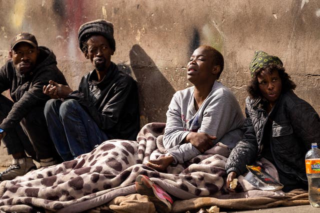 Homeless people sit near the scene of the fire