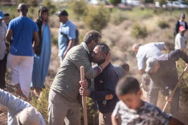 People comfort each other while digging graves for victims of the earthquake