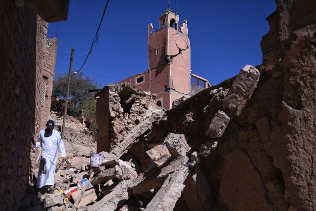 A man walks amid the rubble in front of a damaged mosque in Moulay Brahim in the province of Al Haouz 