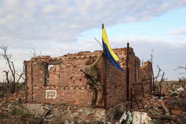 An assault unit commander from the 3rd Assault Brigade raises the Ukrainian flag as a symbol of liberation of the frontline village of Andriivka, Donetsk region