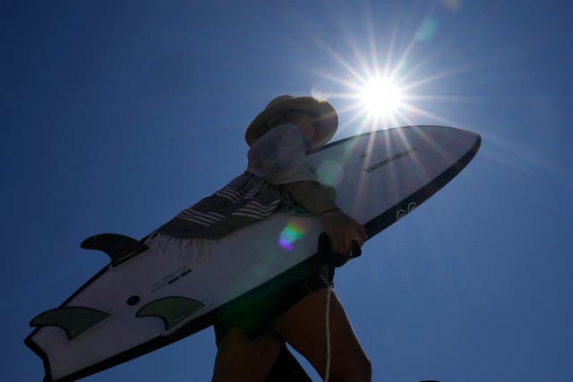 A woman carries her surfboard at Bondi Beach in Sydney on Tuesday