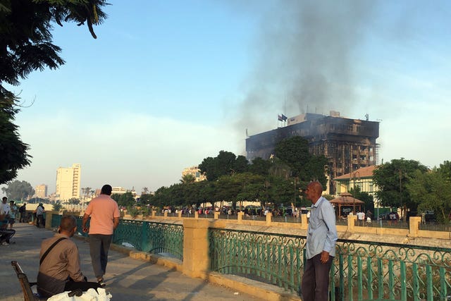 People look on as smokes rises from the burning police headquarters
