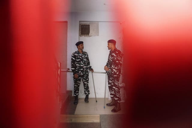 Security officers stand guard outside the office of NewsClick