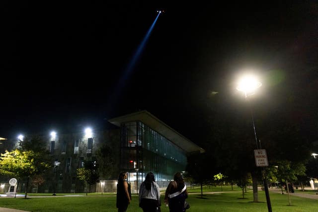 Students watch as a police helicopter flies over Morgan State University after a shooting in Baltimore