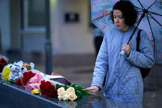 A woman lays flowers in front of the Israeli embassy in Moscow, Russia