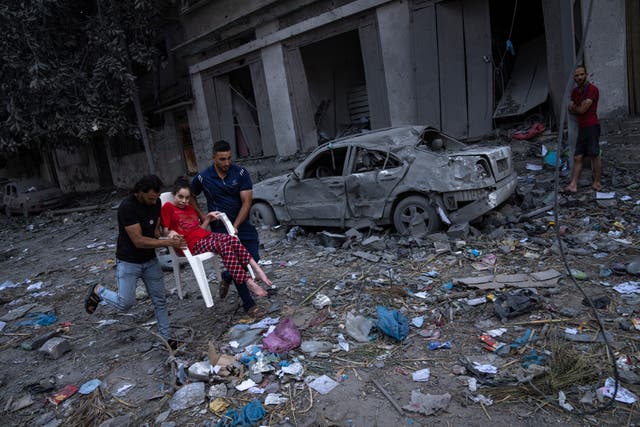 Palestinians walk amid the rubble following Israeli airstrikes that hit a neighbourhood in Gaza City 