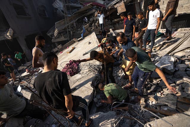 Palestinians search for bodies and survivors in the rubble of a residential building levelled in an Israeli airstrike 