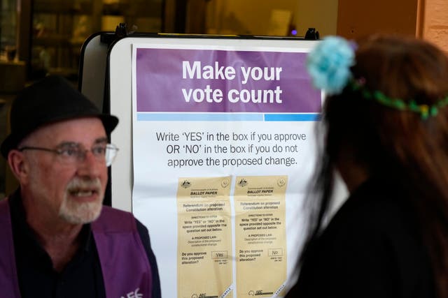 A volunteer assists a woman at a polling station