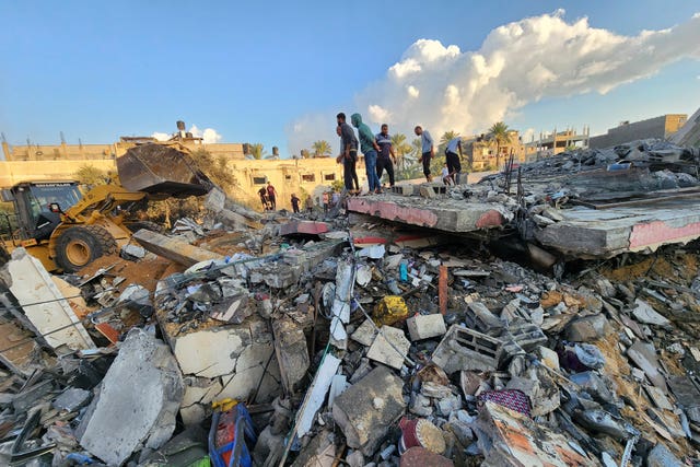 Palestinians stand amid the rubble of a building destroyed in Israeli airstrikes in Deir el-Balah, Gaza Strip 
