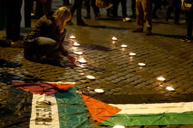 A girl sits by candles during a torchlight demostration in solidarity with Gaza Strip Palestinians in Rome on Wednesday