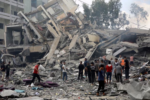 Palestinians inspect the damage of a destroyed building following Israeli air strikes on Gaza City 