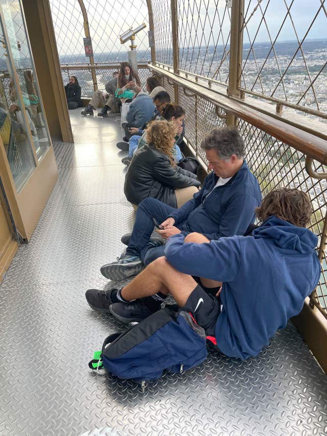 Visitors stranded at the top of the Eiffel Tower while police and firefighters dealt with a man climbing on the structure wait for the lifts to reopen in Paris