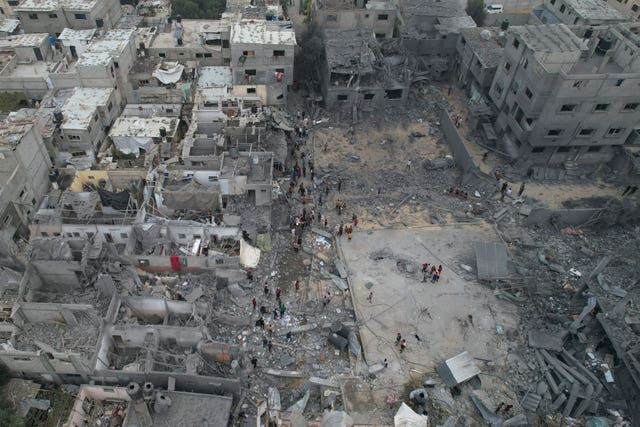 Palestinians walk among destroyed buildings in the Nusseirat refugee camp in the Gaza Strip on Sunday