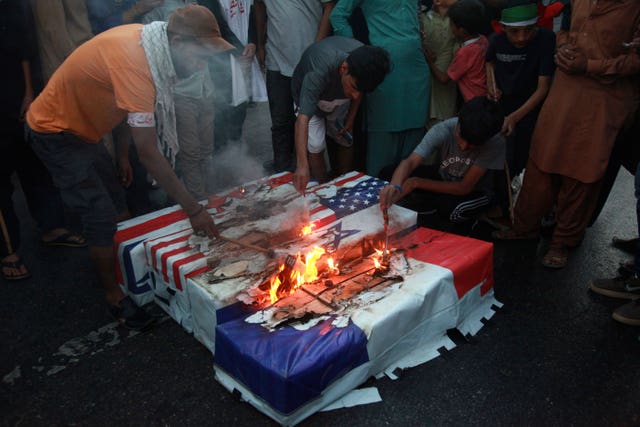 Supporters burn representations of Israeli, US, English and French flags, during a protest against Israeli airstrikes on Gaza, in Karachi, Pakistan