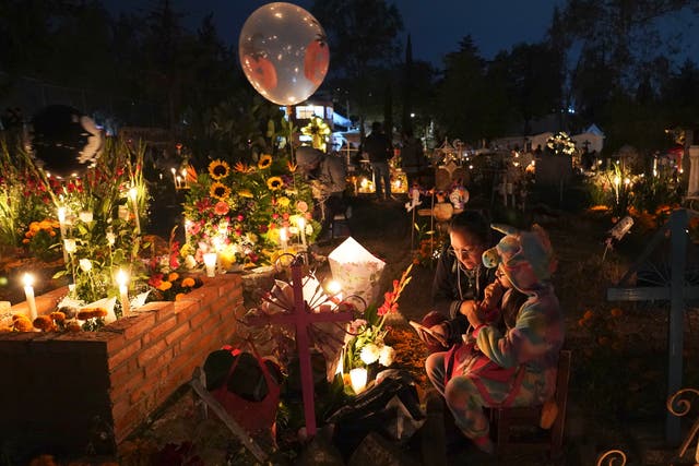 People sit around a child’s tomb in the San Gregorio Atlapulco cemetery