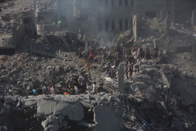 Palestinians look for survivors in the rubble of a destroyed building following an Israeli air strike in the Gaza Strip