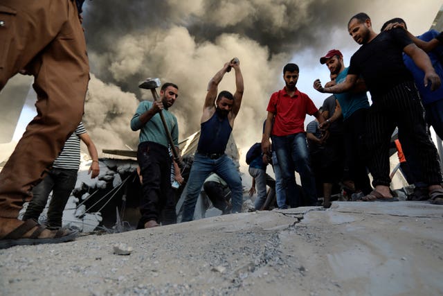 Palestinians strike the concrete while looking for survivors under the rubble of a destroyed house following an Israeli airstrike in Gaza City on Saturday