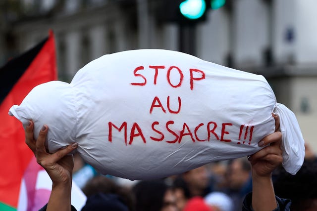 A mock child’s body is carried during a demonstration in Paris